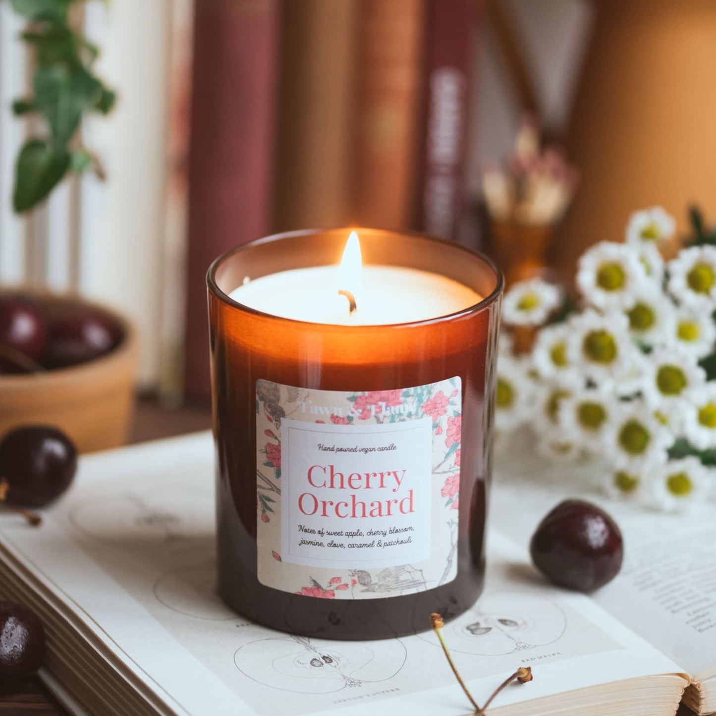 cherry orchard vegan candle with cherries and flowers and books.