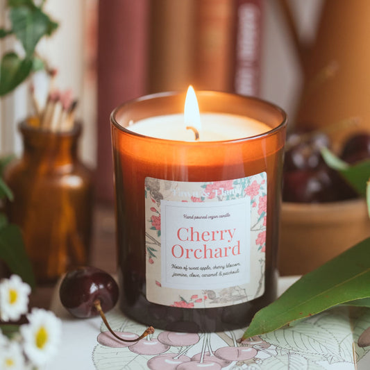 cherry orchard vegan candle with cherries and flowers and books.