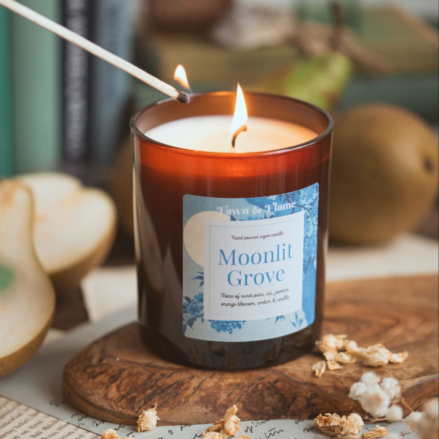moonlit grove vegan candle with match and pears and flowers and books.
