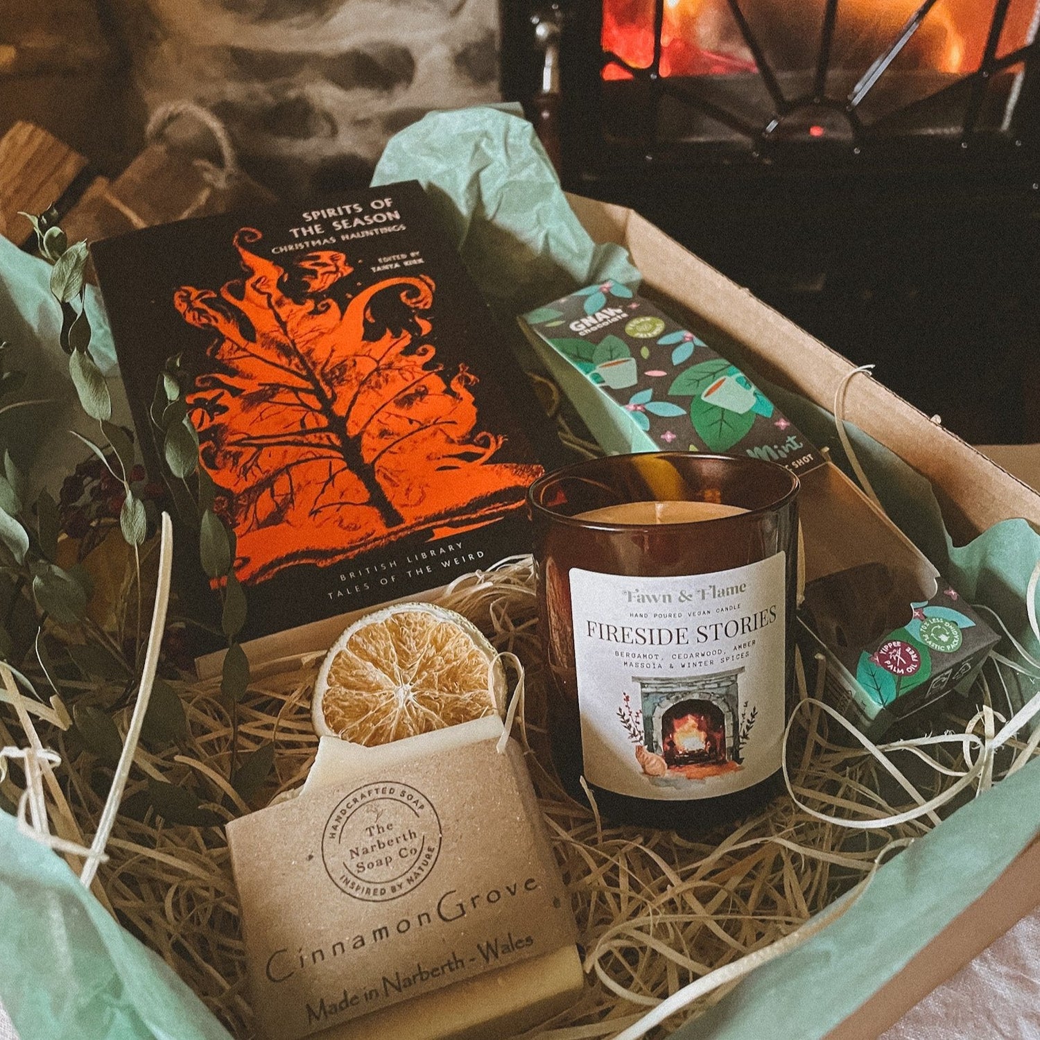 A beautifully arranged gift box featuring a hand-poured candle, a choice of books, indulgent hot chocolate, and natural soap, perfect for cozy reading rituals.