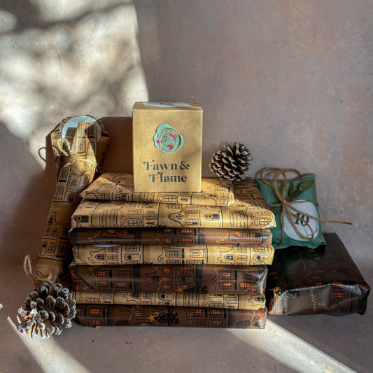 Stack of books with decorative packaging and pinecones on a textured surface