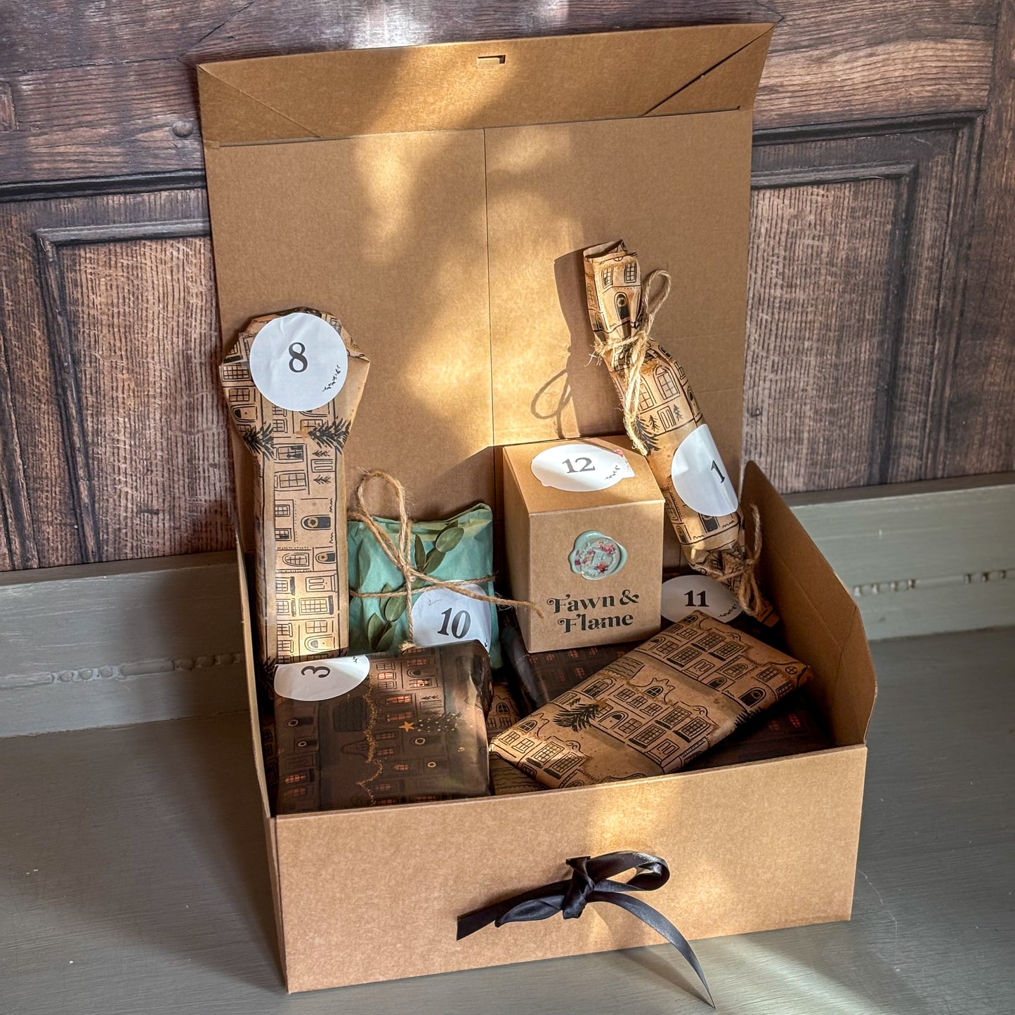 Gift set with candles and packaging in a cardboard box on a wooden floor.