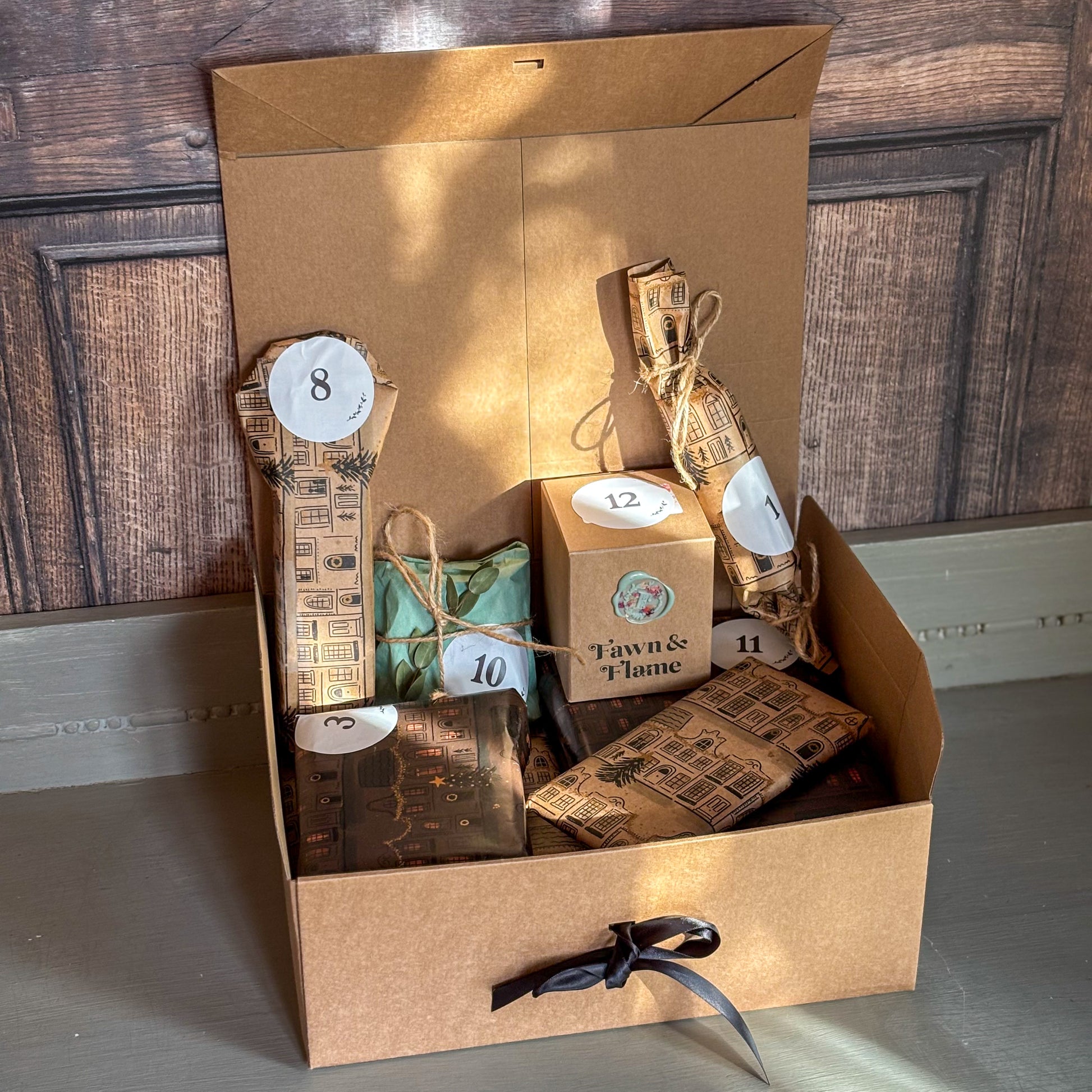 Gift set with candles and packaging in a cardboard box on a wooden floor.