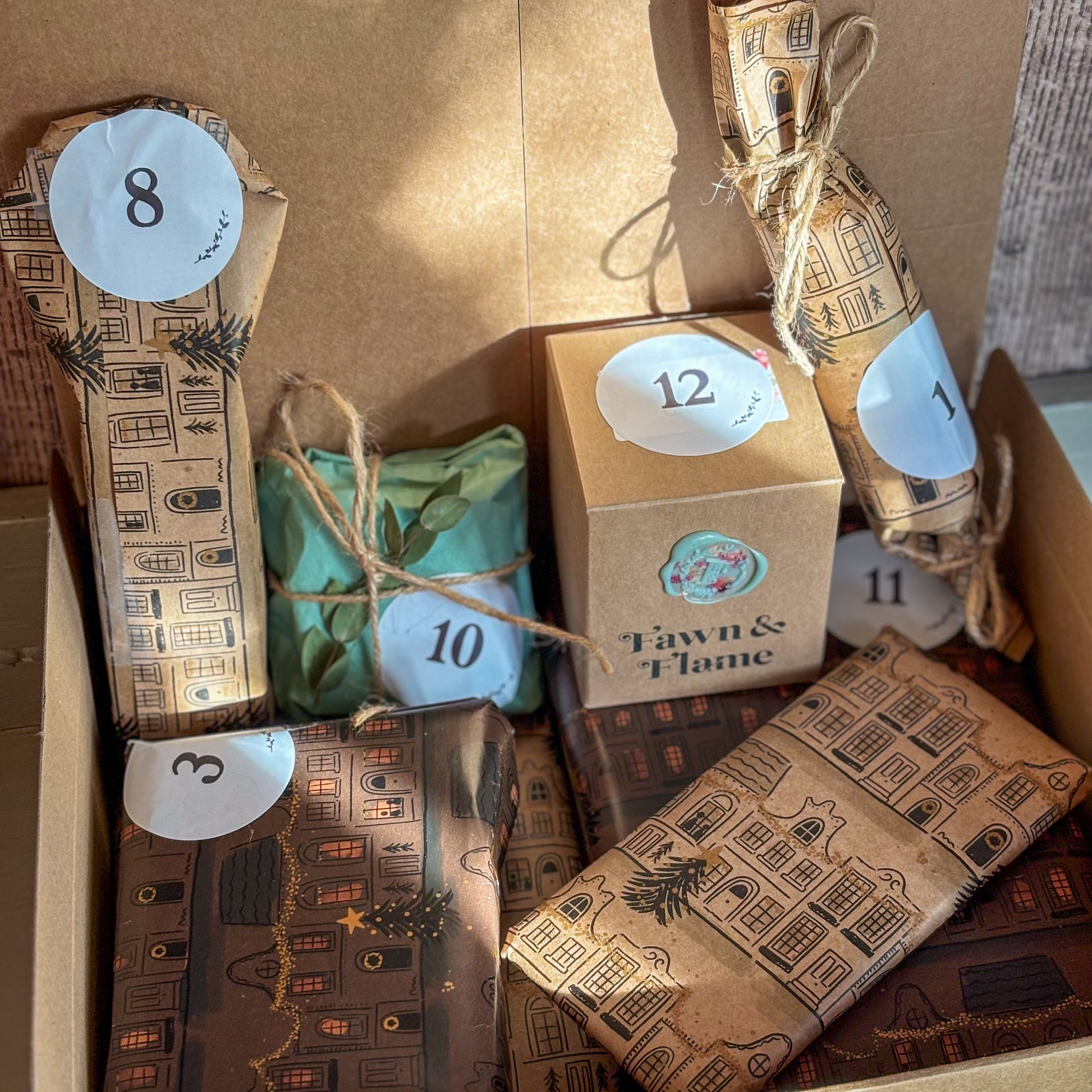 Box of wrapped gifts with decorative ribbons and numbered labels, featuring 'Fawn & Flame' branding.